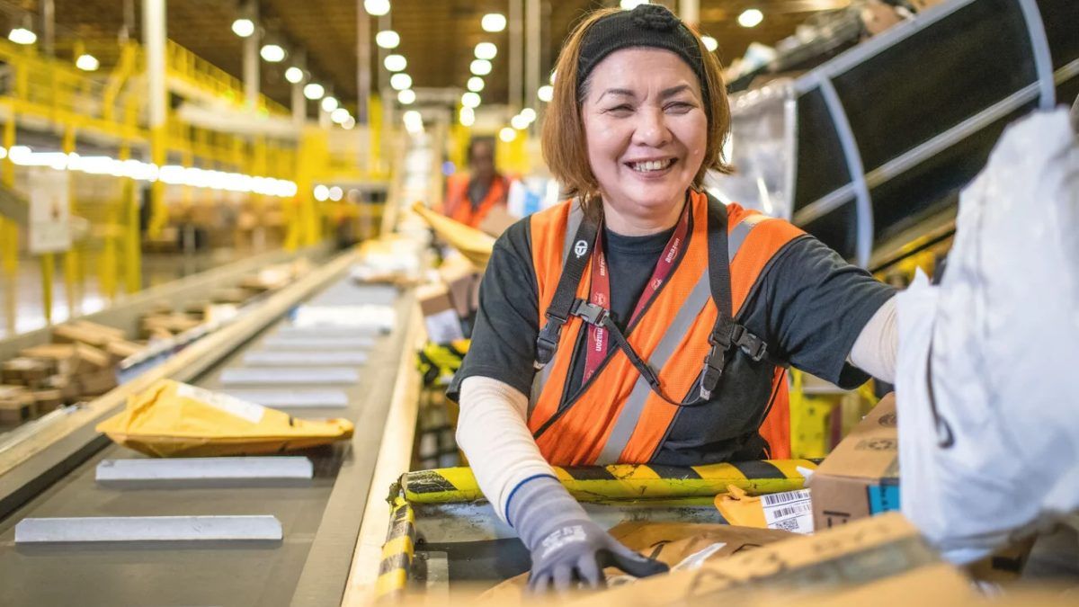 Una trabajadora de Amazon sonríe mientras prepara paquetes.