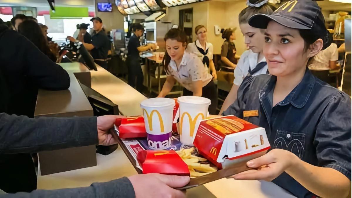 Una trabajadora de McDonalds entrega el menú a un cliente