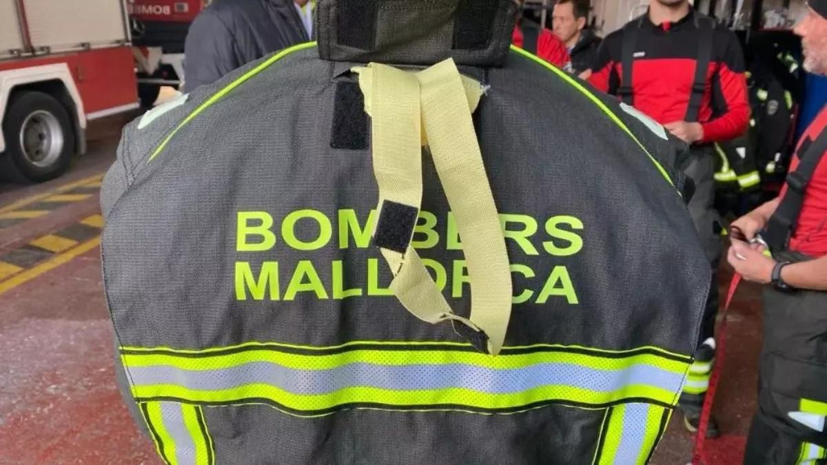 Imagen de una chaqueta de bomberos de Mallorca, junto a varios profesionales en un garaje.