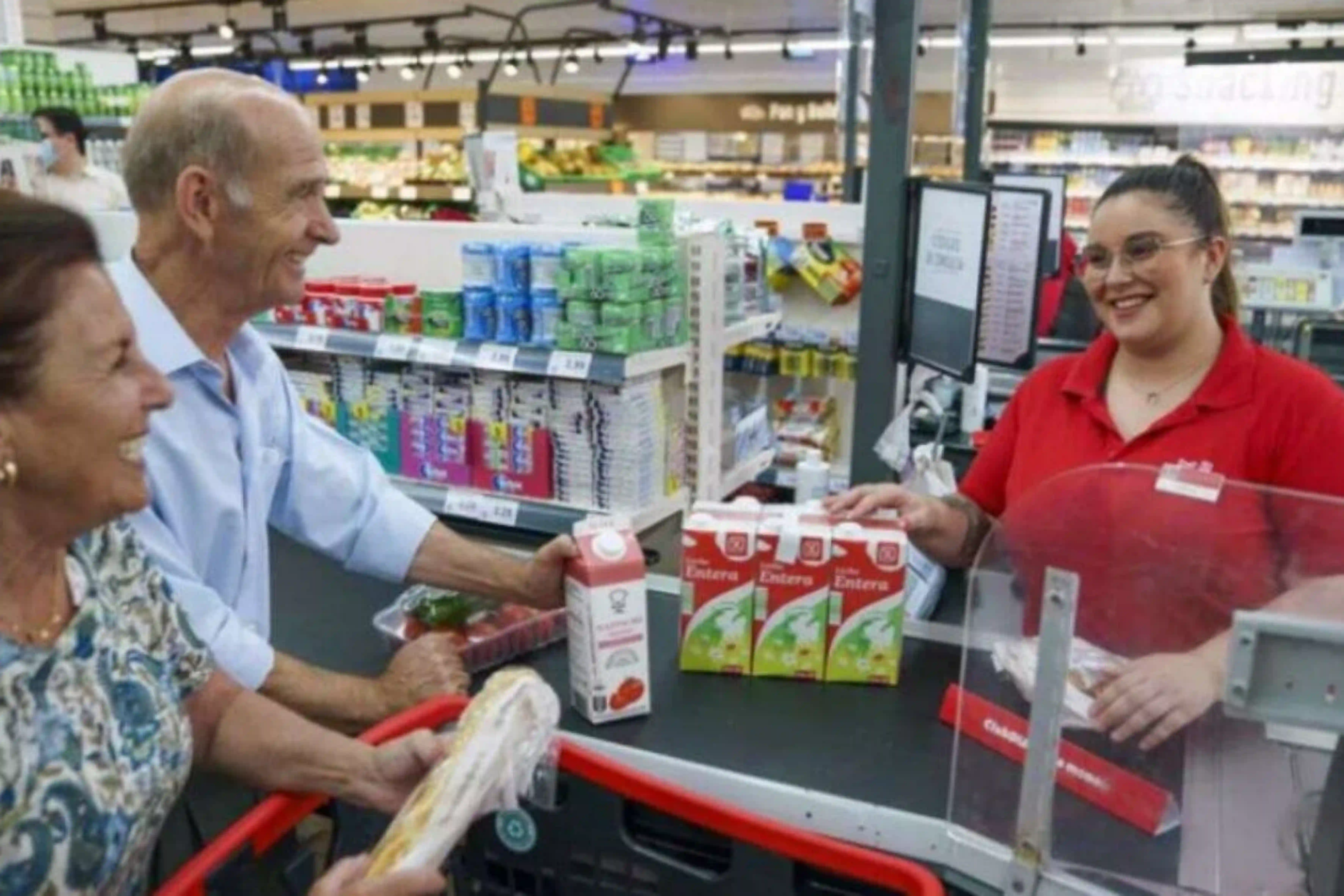 Trabajadora de supermercados DIA atiende a unos clientes