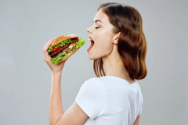 Una mujer comiendo una hamburguesa