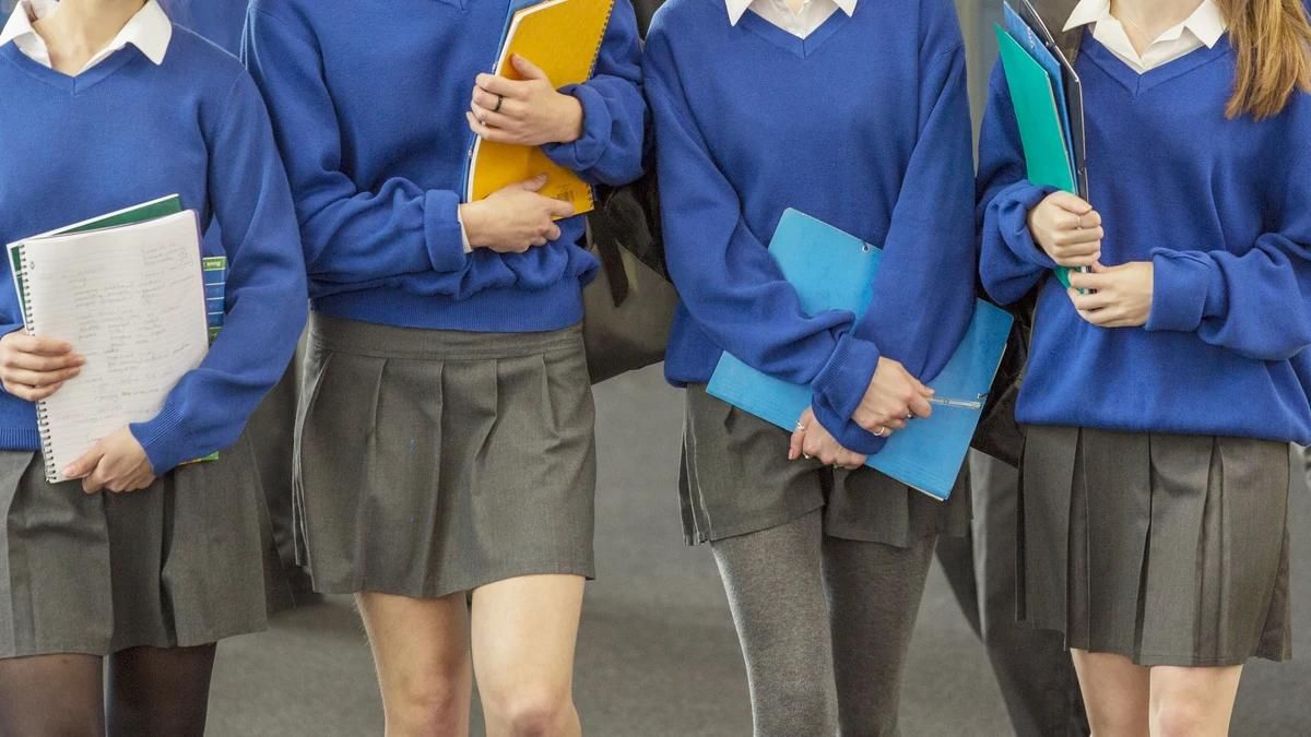 Grupo de estudiantes con carpetas en la mano y uniforme escolar.