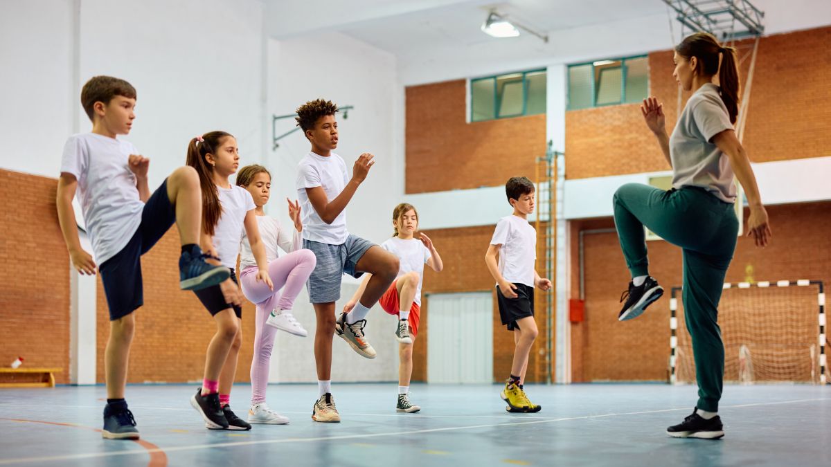 Una mujer entrena con algunos niños en una pista deportiva