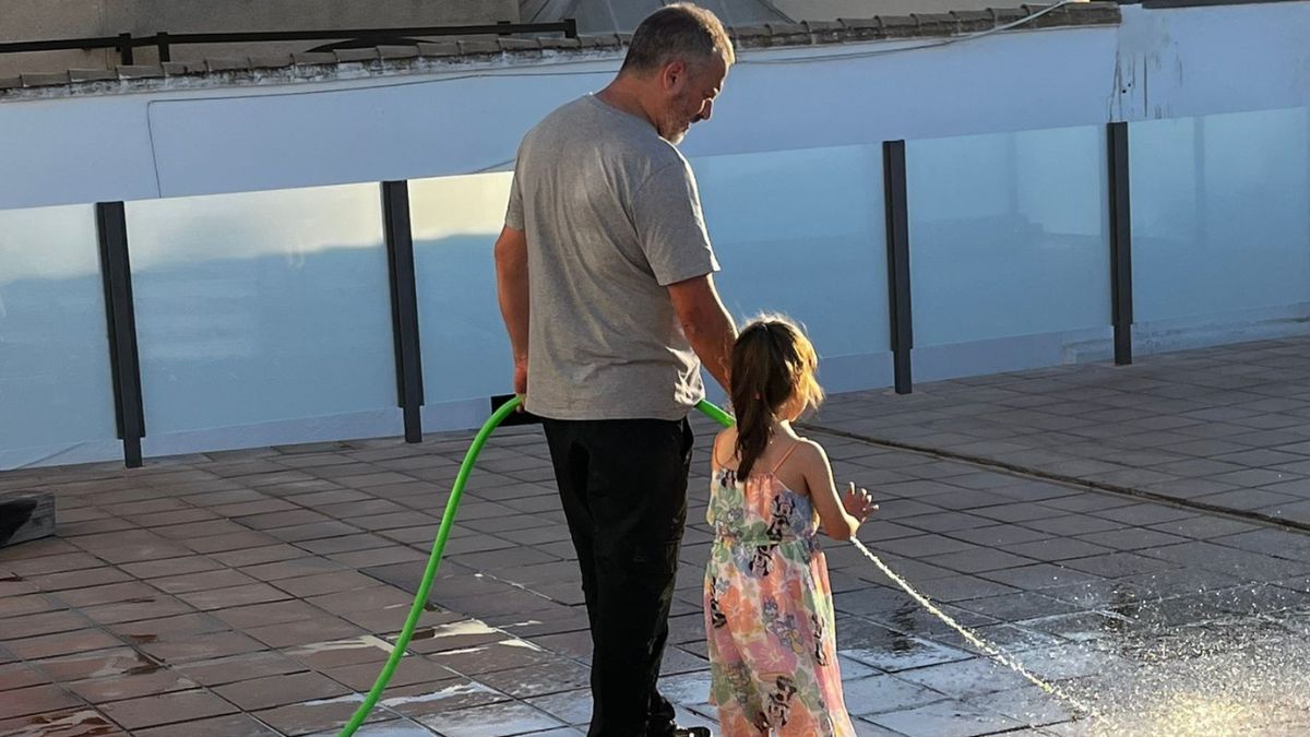 Trabajador del establecimiento con la niña limpiando la calle.