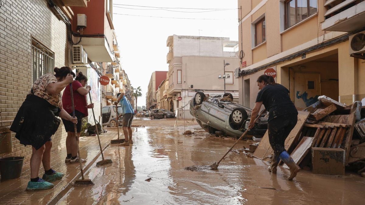 Varias mujeres barren en una calle inundada.